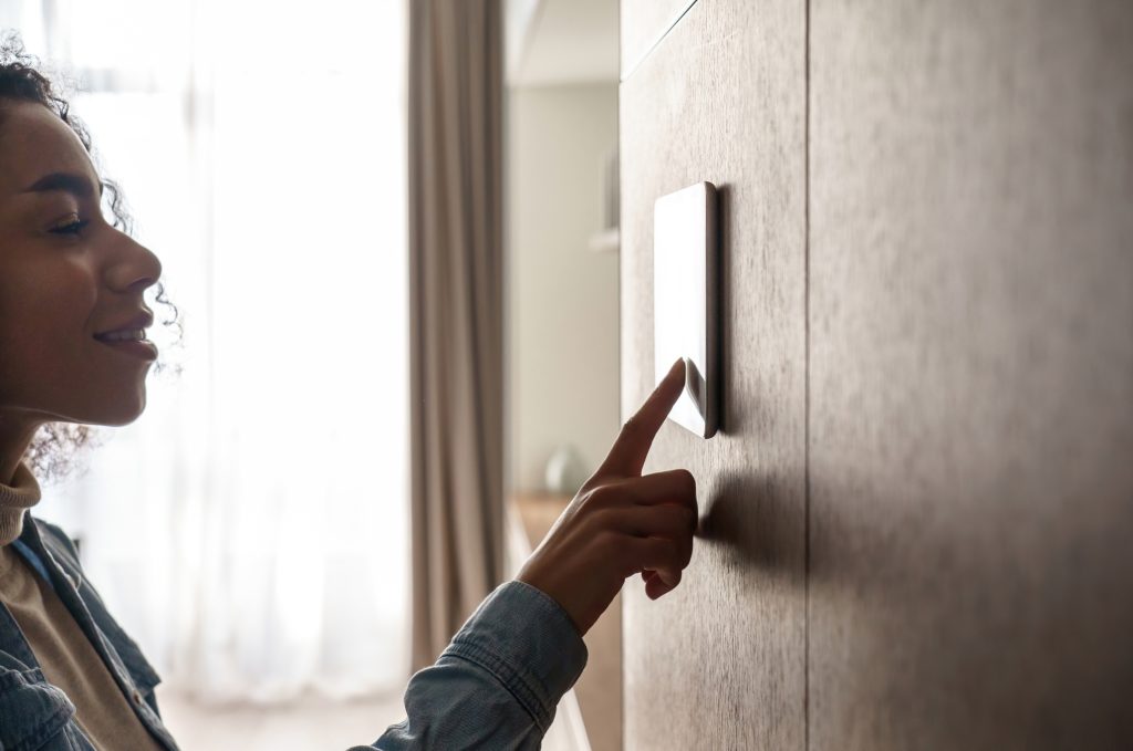 woman tapping a sleek wall-fixed control panel