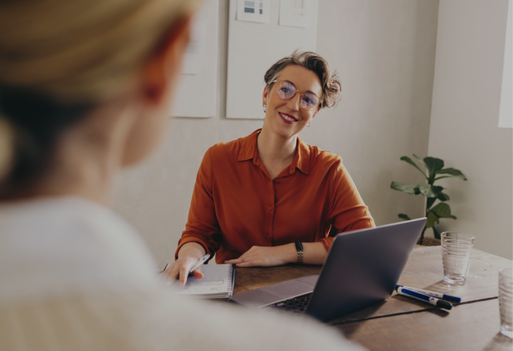 Woman at desk smiling at another woman