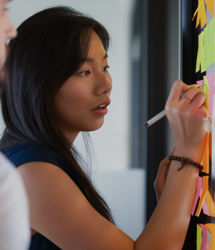 Woman writing on post-it notes on a glass wall