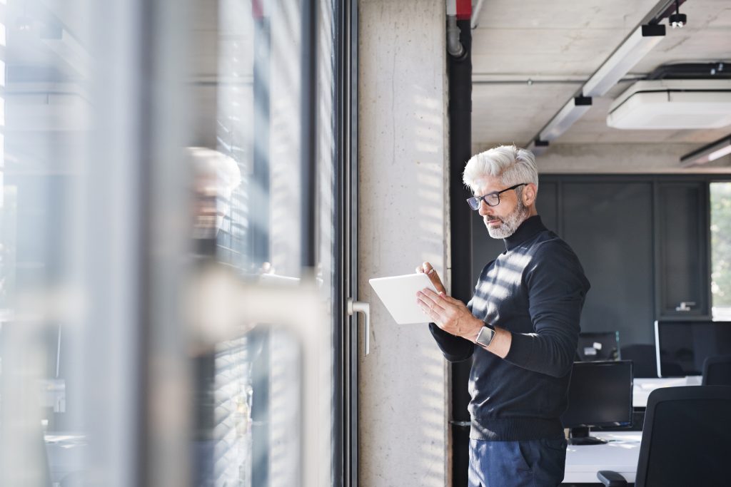 man looking at papers in front of glass wall