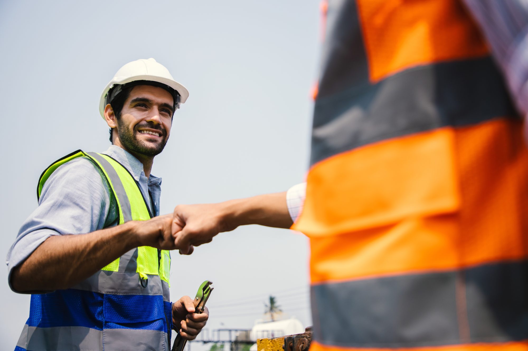 Two engineers inPPE bumping fists