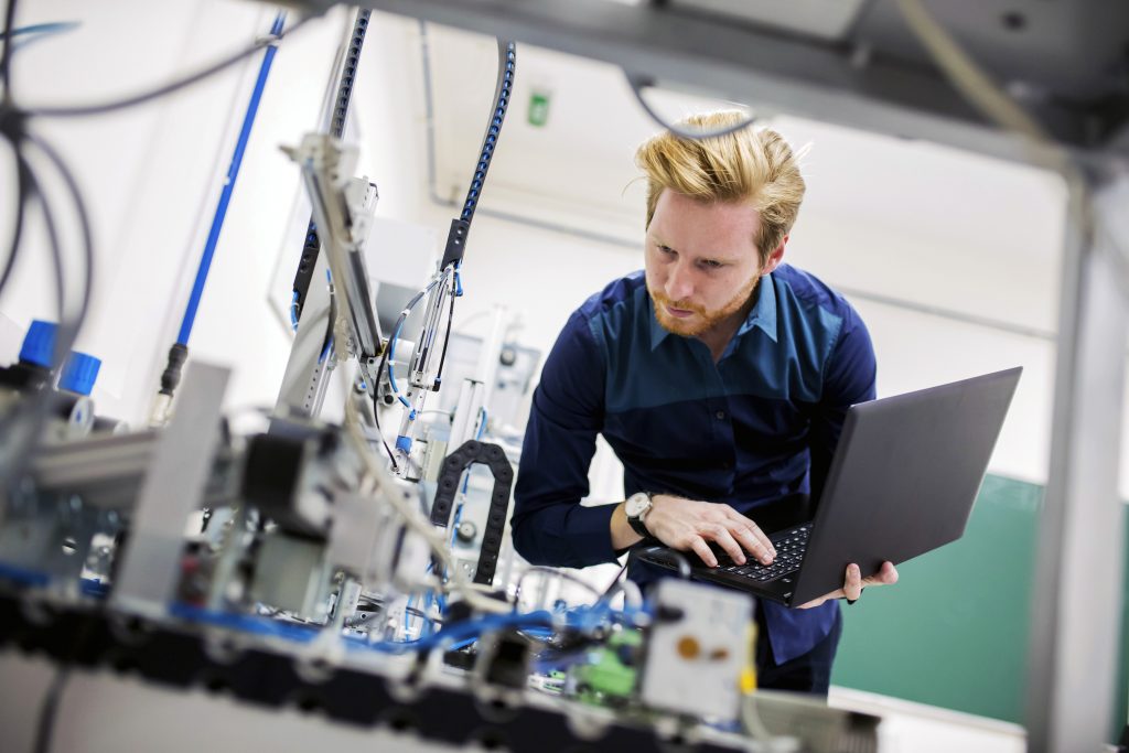 Engineer in the factory holding laptop and looking at project