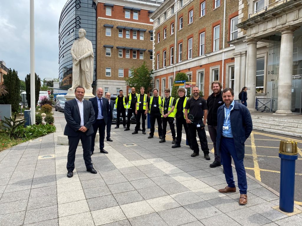 A group of men in suits and hi-vis vests in fron of King's College